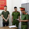 Lực lượng chức năng đọc lệnh khởi tố, bắt tạm giam phóng viên Nguyễn Trọng Hùng. (Ảnh: TTXVN phát)