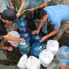 Người dân xếp hàng chờ lấy nước miễn phí tại Nhà máy nước Hạ Đình (địa chỉ, số 14 ngõ 192 phố Hạ Đình). (Ảnh: Thành Đạt/TTXVN)
