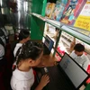 Các em học sinh trường Tiểu học Him Lam (thành phố Vị Thanh, tỉnh Hậu Giang) đọc sách, báo tại Xe thư viện lưu động đa phương tiện. (Ảnh: Duy Khương/TTXVN)