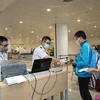 Nhân viên y tế kiểm tra phiếu khai báo y tế của hành khách trước khi làm thủ tục nhập cảnh tại cửa khẩu Sân bay quốc tế Nội Bài (Hà Nội), chiều 7/3. (Ảnh: Dương Giang/TTXVN)