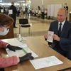 Tổng thống Nga Vladimir Putin (phải) làm thủ tục tại điểm bỏ phiếu trưng cầu dân ý về sửa đổi Hiến pháp ở Moskva ngày 1/7/2020. (Ảnh: AFP/TTXVN)