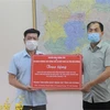 Nhà báo Đinh Mạnh Tú, Trưởng Cơ quan thường trú TTXVN tại tỉnh Hải Dương trao bảng tượng trưng bảo hộ, khẩu trang y tế cho Trung tâm kiểm soát bệnh tật, Sở Y tế Hải Dương. (Ảnh: Mạnh Minh/TTXVN)