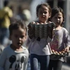 Trẻ em nhận thức ăn và nước uống cứu trợ sau vụ cháy trại tị nạn Moria trên đảo Lesbos, Hy Lạp, ngày 10/9/2020. (Ảnh: AFP/TTXVN)