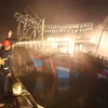 Lực lượng chữa cháy nỗ lực dập lửa trên tàu cá. (Ảnh: Nguyễn Oanh/TTXVN)