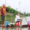 Hai cha con ở thôn Bình Tiến (xã Tân Lâm Hương, huyện Thạch Hà, Hà Tĩnh) dùng bè chuối ra để nhận hàng cứu trợ. (Ảnh: Hoàng Ngà/TTXVN)