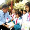 Các nhà hảo tâm trao tặng tập vở cho học sinh vùng lũ xã An Ninh, huyện Quảng Ninh. (Ảnh: Võ Dung/TTXVN)