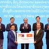 Thứ trưởng Bộ Ngoại giao Nguyễn Quốc Dũng (bên phải) trao tượng trưng 1.000 tấn gạo cho đại diện Đại sứ quán Lào tại Việt Nam trước sự chứng kiến của Thủ tướng Nguyễn Xuân Phúc. (Ảnh: Thống Nhất/TTXVN)