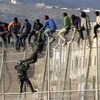 Lực lượng dân phòng nỗ lực ngăn người di cư vượt hàng rào biên giới để vào Melilla, vùng lãnh thổ thuộc Tây Ban Nha ở Bắc Phi, ngày 15/10/2014. (Ảnh: EPA/TTXVN)