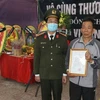 Trao Quyết định thăng cấp bậc hàm từ Thiếu tá lên Trung tá cho gia đình đồng chí Vi Văn Luân. (Ảnh: Trịnh Duy Hưng/TTXVN)
