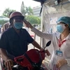 Đo thân nhiệt cho người dân đến khám bệnh tại Bệnh viện Thống Nhất Thành phố Hồ Chí Minh. (Ảnh: Đinh Hằng/TTXVN)