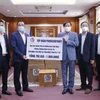Chủ tịch Tập đoàn Phongsubthavy của Lào, ông Phongsavath Senaphuan (trái) đang trao tượng trưng tấm biển số tiền và vật tư y tế trị giá 1 triệu USD cho Đại sứ Nguyễn Bá Hùng để ủng hộ Quỹ phòng chống COVID-19 của Việt Nam. (Ảnh: Phạm Kiên/TTXVN)