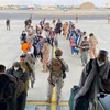 Người dân được lực lượng an ninh hỗ trợ lên máy bay sơ tán khỏi Afghanistan, tại sân bay quốc tế ở Kabul. (Ảnh: REUTERS/TTXVN)