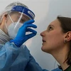 Nhân viên y tế lấy mẫu xét nghiệm COVID-19 cho người dân tại điểm xét nghiệm ở Berlin, Đức ngày 17/2/2021. (Ảnh: AFP/TTXVN)