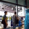 Hành khách tới sân bay Nội Bài phải đo kiểm tra thân nhiệt. (Ảnh: Huy Hùng/TTXVN)