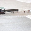 Lực lượng chức năng hỗ trợ những người bị mắc kẹt giữa đập Nam Thạch Hãn di chuyển ra khỏi vùng nguy hiểm, trước khi đưa vào bờ. (Ảnh: Nguyên Lý/TTXVN)