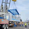Công tác cẩu toa xe từ tàu xuống xe chuyên dụng để vận chuyển về depot Long Bình trong đợt vận chuyển đoàn tàu vào tháng 7. (Ảnh: TTXVN phát)