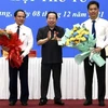 Ông Mai Văn Huỳnh (giữa), Chủ tịch HĐND tỉnh tặng hoa chúc mừng tân Phó Chủ tịch UBND tỉnh Lê Quốc Anh (phải). (Ảnh: Lê Sen/TTXVN)