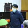 Cảnh sát dẫn giải cựu Chủ tịch UBND thành phố Hà Nội Nguyễn Đức Chung vào phòng xét xử. (Ảnh: TTXVN)