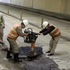 Đơn vị quản lý hầm xử lý gia cố tạm thời những vị trí nền đường bị hư hỏng bằng thảm nhựa đường. (Ảnh: Đỗ Trưởng/TTXVN)