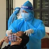 Nhân viên y tế Trạm y tế lưu động số 1 xã Tân Triều, huyện Thanh Trì lấy mẫu xét nghiệm sàng lọc cho người dân trước khi hết cách ly, điều trị. (Ảnh: Hoàng Hiếu/TTXVN)