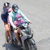 Một gia đình phải mặc áo chống nắng khi phải di chuyển trên đường Giải Phóng lúc 11h40. (Ảnh: Hoàng Hiếu/TTXVN)