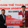 Đại sứ Nguyễn Huy Tăng (trái) tặng quà, chúc mừng Đoàn thể thao Việt Nam. (Ảnh: Hoàng Minh/TTXVN)