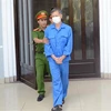 Cơ quan chức năng dẫn giải cựu Giám đốc CDC Đà Nẵng ra xe sau khi kết thúc phiên tòa sáng 25/8. (Ảnh: Văn Dũng/TTXVN)