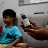Một phụ huynh cầm chai thuốc ho con trai anh sử dụng dẫn đến tổn thương thận cấp tính tại Jakarta, Indonesia, ngày 11/2/2023. (Ảnh: AFP/TTXVN)