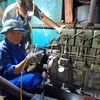 Cán bộ kỹ thuật Âu tàu đảo Sinh Tồn giúp ngư dân sửa chữa máy phát điện của tàu cá QNg 90431 TS. Ảnh: TTXVN phát