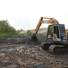 Một vụ đổ bùn thải ra môi trường nhưng không thực hiện lót bạt chống thấm. (Ảnh: Minh Phú - TTXVN)