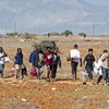 Người di cư rời trại tị nạn Pournara ở CH Cyprus. (Ảnh: AFP/TTXVN)