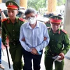 Lực lượng chức năng dẫn giải bị cáo Nguyễn Thanh Long (cựu Bộ trưởng Bộ Y tế) đến phiên tòa. (Ảnh: Phạm Kiên/TTXVN)