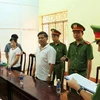 Cơ quan Công an thực hiện lệnh khởi tố bị can và bắt tạm giam đối với Nguyễn Hữu Hóa (áo trắng, bên phải). (Ảnh: TTXVN phát)