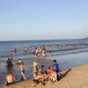 Bãi biển Thiên Cầm hút hút lượng lớn người lớn và trẻ em ra tắm tránh nắng nóng. (Ảnh: Phan Quân/TTXVN)