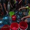 Người dân xếp hàng lấy nước sạch. (Ảnh: PV/Vietnam+)