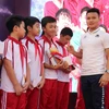 Quang Hải tặng sách cho các học sinh trường THCS Nam Trung Yên. (Ảnh: Vietnam+)