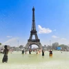 Người dân tránh nóng bên vòi phun nước tại Paris, Pháp. (Ảnh: THX/TTXVN)