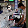 Nhân viên y tế kiểm tra thân nhiệt cho người dân tại thành phố Trạm Giang, tỉnh Quảng Đông, Trung Quốc, ngày 6/2/2020. (Ảnh: THX/TTXVN)
