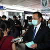 Bộ trưởng Y tế Thái Lan Anutin Charnvirakul (phải) phát khẩu trang cho hành khách tại một nhà ga ở Bangkok. (Ảnh: AFP/TTXVN)