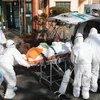 Nhân viên y tế chuyển bệnh nhân nhiễm COVID-19 lên xe cứu thương tại thành phố Daegu, Hàn Quốc. (Ảnh: AFP/TTXVN)