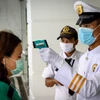 Nhân viên an ninh kiểm tra thân nhiệt người dân nhằm ngăn chặn sự lây lan của dịch COVID-19 tại Bangkok. (Ảnh: AFP/TTXVN)