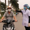 Lực lượng chức năng kiểm tra thân nhiệt cho người tham gia giao thông tại Bắc Ninh. (Ảnh: Thanh Thương/TTXVN)