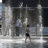 Trẻ em chơi đùa bên vòi phun nước để tránh nắng nóng tại Milan, Italy, ngày 26/6/2019. (Ảnh: AFP/ TTXVN)