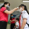 Học sinh trường Tiểu học Nghĩa Tân, quận Cầu Giấy được đo thân nhiệt và sát khuẩn tay trước khi vào lớp. (Ảnh: Thanh Tùng/TTXVN)