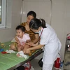 Bác sỹ thăm khám cho trẻ mắc tay chân miệng tại bệnh viện Sản nhi tỉnh Ninh Bình. (Ảnh: Thùy Dung/TTXVN)