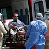 Nhân viên y tế chuyển bệnh nhân COVID-19 tới bệnh viện ở Brasilia, Brazil, ngày 25/3. (Ảnh: THX/TTXVN)