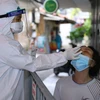Lực lượng y tế lấy mẫu xét nghiệm SARS-CoV-2 cho những người có nguy cơ cao. (Ảnh: Hoàng Hiếu/TTXVN)