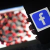Biểu tượng mạng xã hội Facebook và virus corona trên màn hình điện thoại. (Ảnh: AFP/TTXVN)