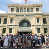Đoàn khách quốc tế chụp ảnh lưu niệm trước Bưu điện Thành phố Hồ Chí Minh. (Ảnh: Mỹ Phương/TTXVN)