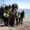 Lực lượng chức năng Anh hỗ trợ người di cư được giải cứu khi đang cố vượt eo biển Manche từ Pháp vào Anh, ngày 16/8/2023. (Ảnh: AFP/TTXVN)
